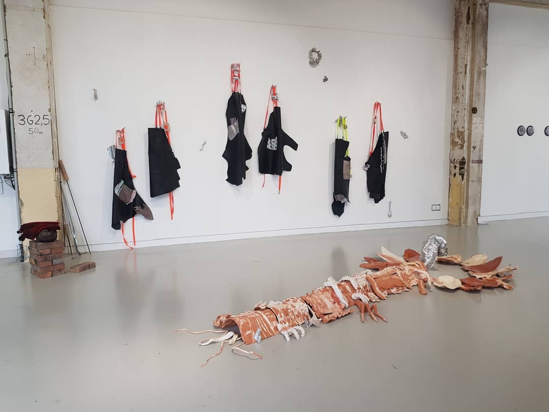 Des tabliers sont accrochés au mur et une sculpture en céramique est au sol